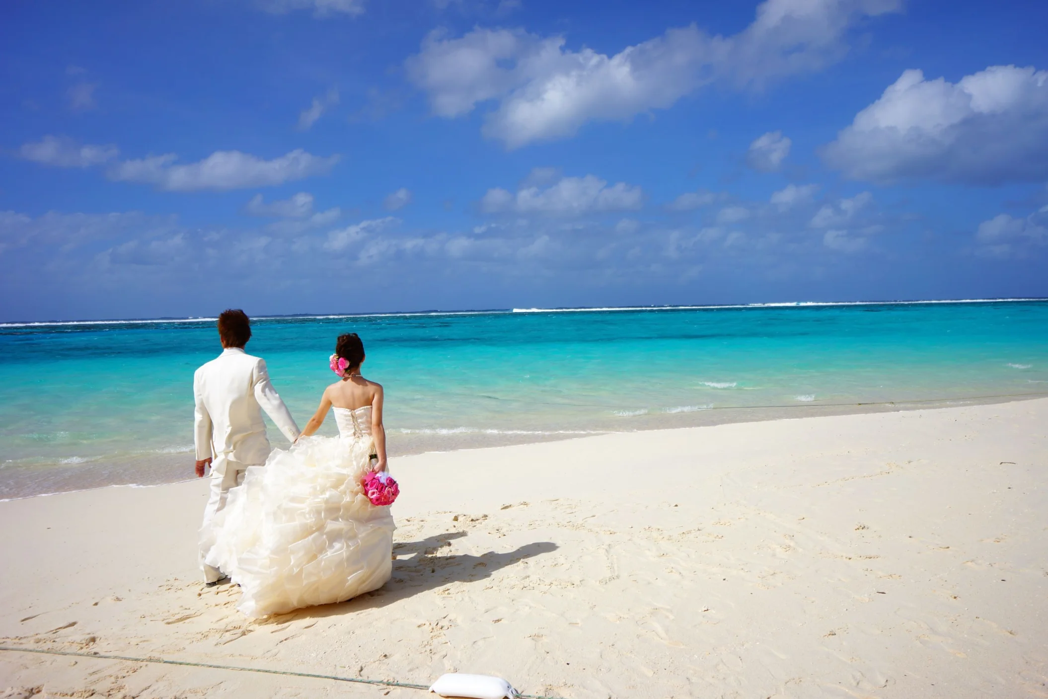 bride and groom on the beach holding hands