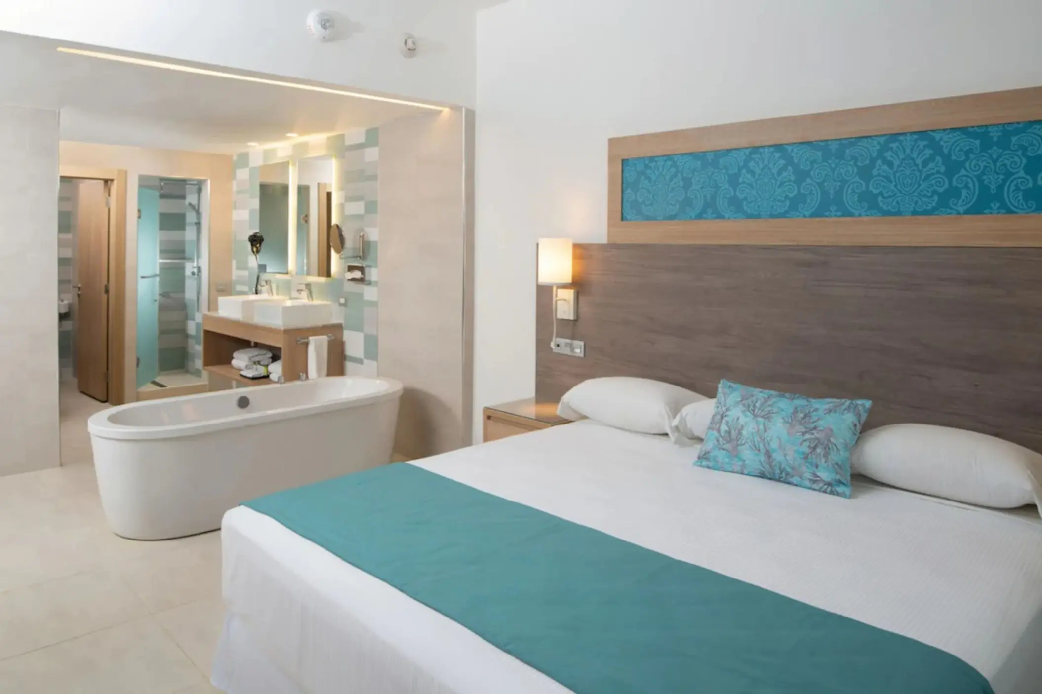 Modern suite with a white soaking tub and teal accents at Riu Palace Tropical Bay, Negril