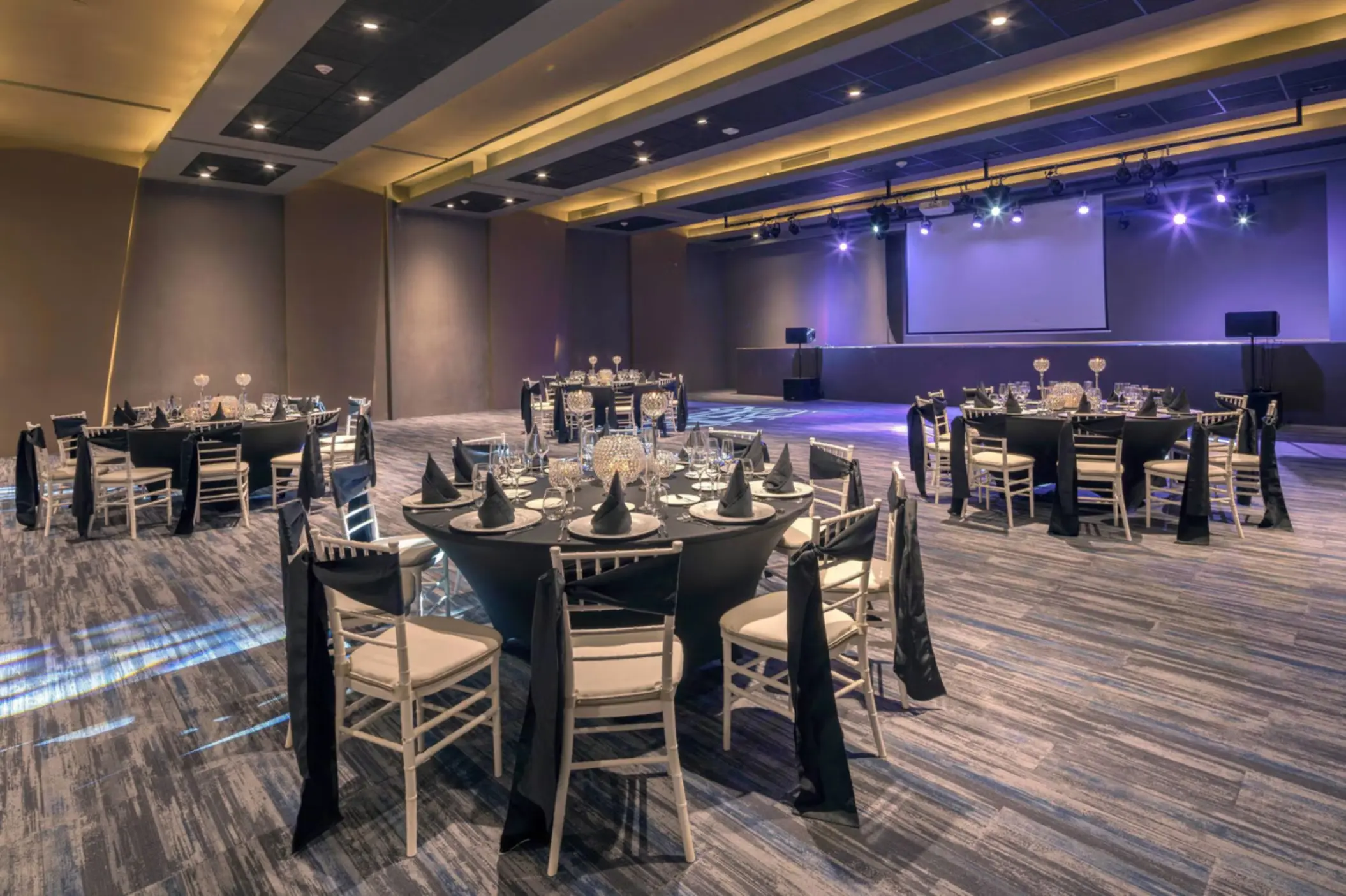 Ballroom wedding reception with round tables and a stage at Royalton Antigua, Five Islands Village