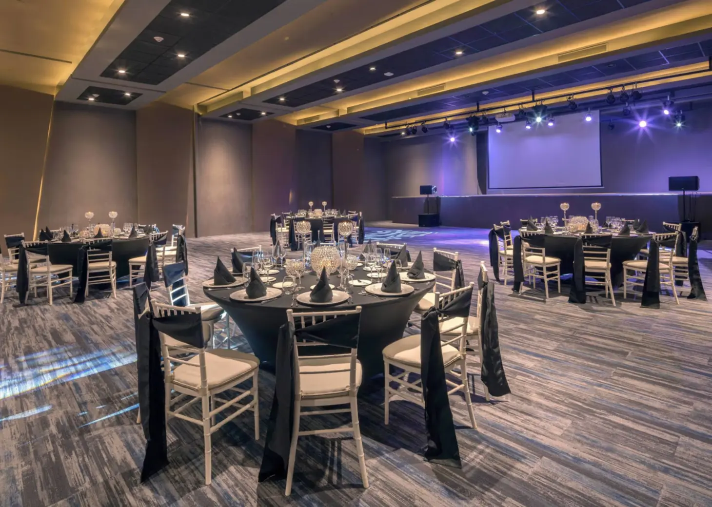Ballroom wedding reception with round tables and a stage at Royalton Antigua, Five Islands Village