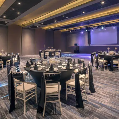 Ballroom wedding reception with round tables and a stage at Royalton Antigua, Five Islands Village