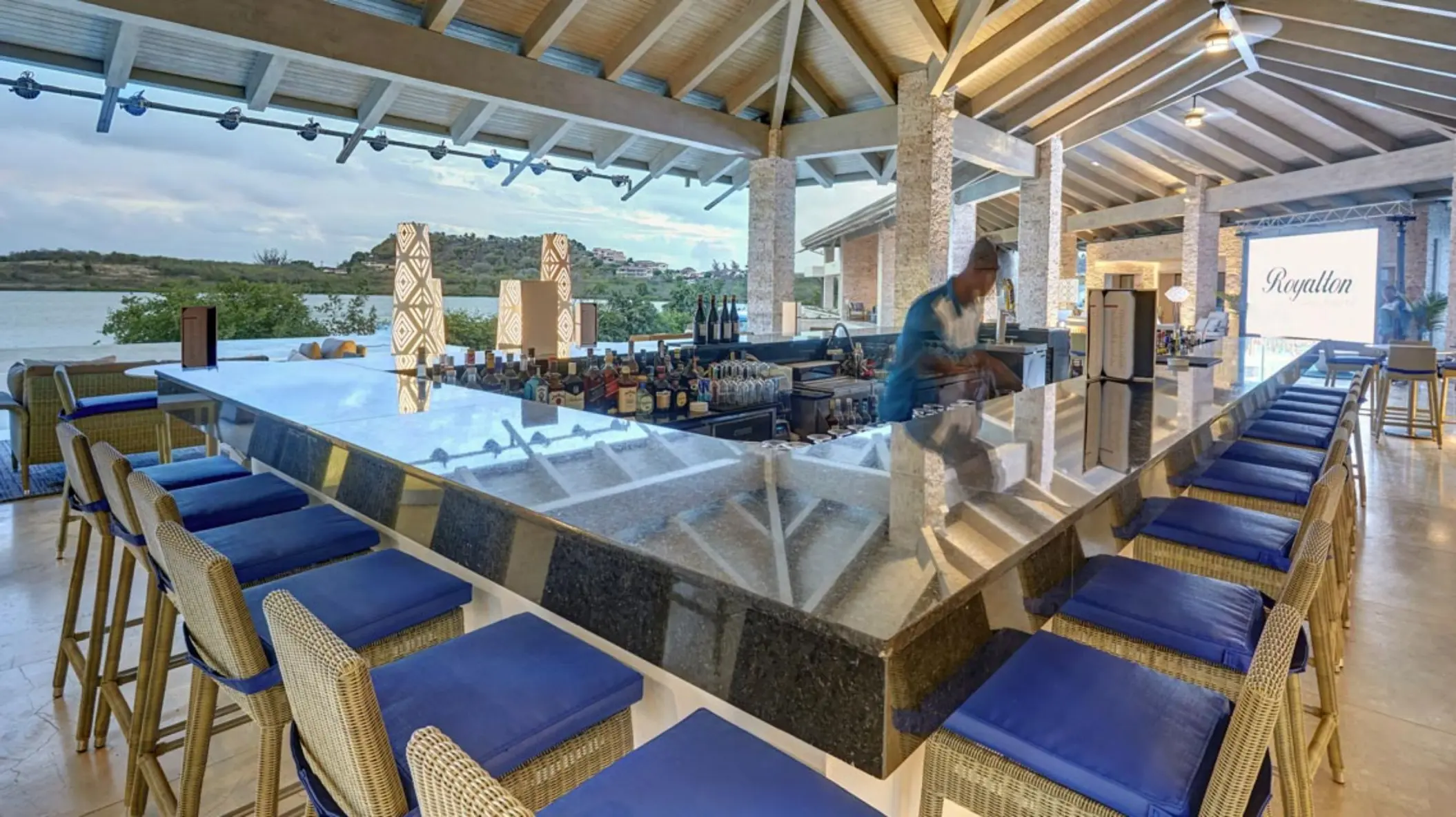 Outdoor bar with blue stools and ocean views at Royalton Antigua, Five Islands Village