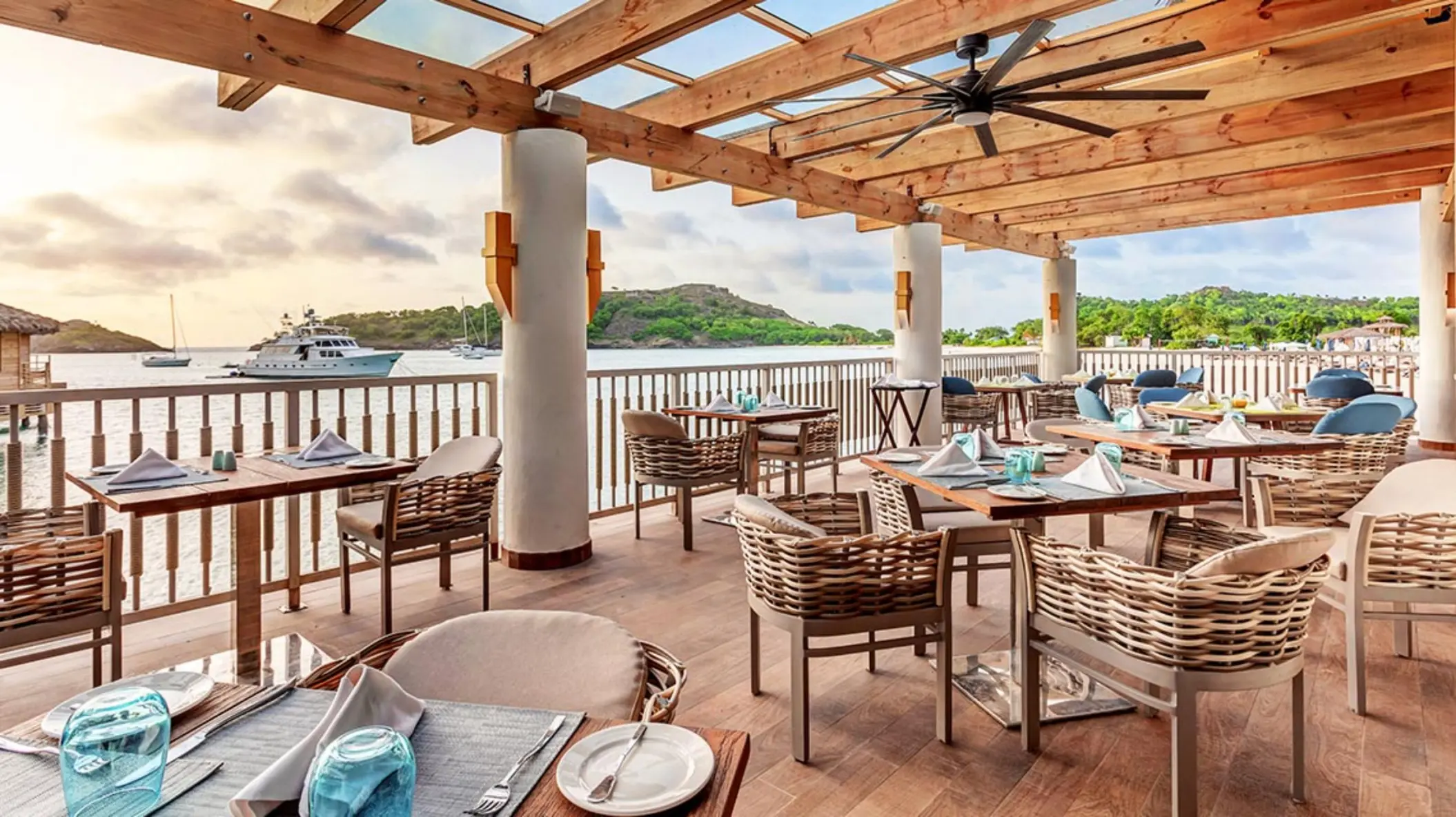 Oceanfront restaurant with outdoor seating under a wooden pergola at Royalton Antigua, Five Islands Village