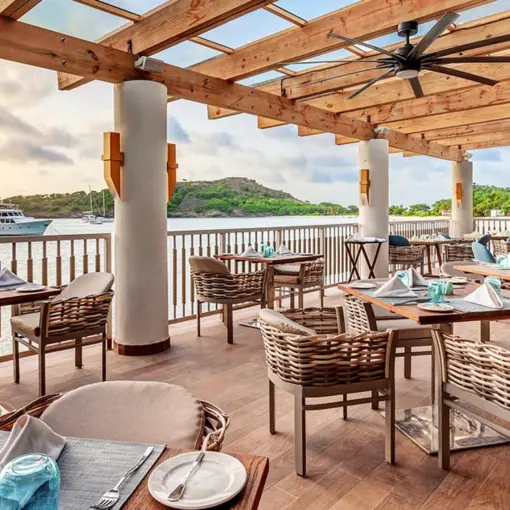 Oceanfront restaurant with outdoor seating under a wooden pergola at Royalton Antigua, Five Islands Village