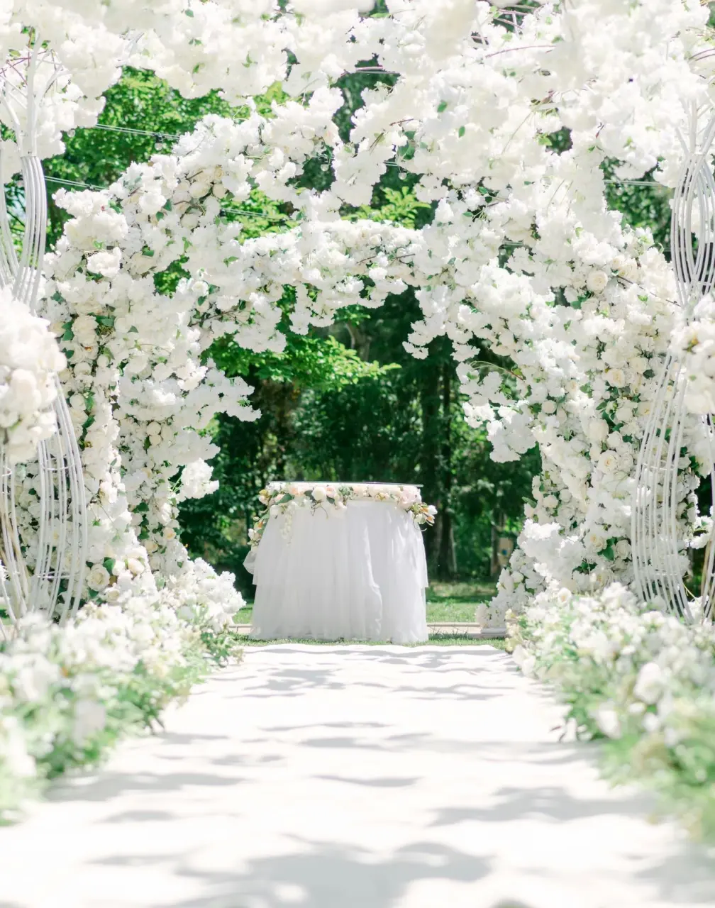 Outdoor wedding ceremony with white floral arches and gold chairs at Royalton Antigua, Five Islands Village