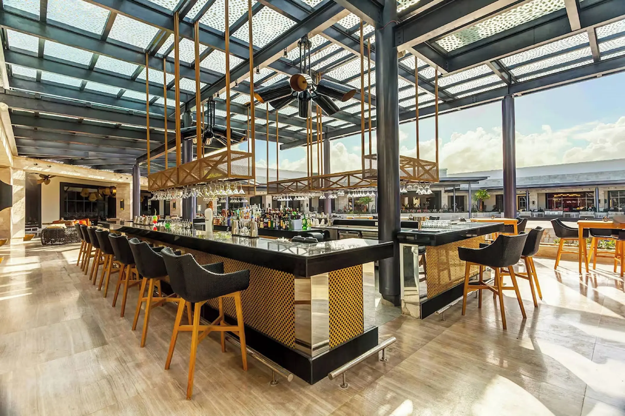 Modern open-air bar with black stools and a glass ceiling at Royalton Bavaro, Punta Cana