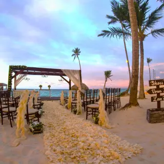Beach wedding ceremony with a wooden arbor and floral aisle at Royalton Bavaro, Punta Cana