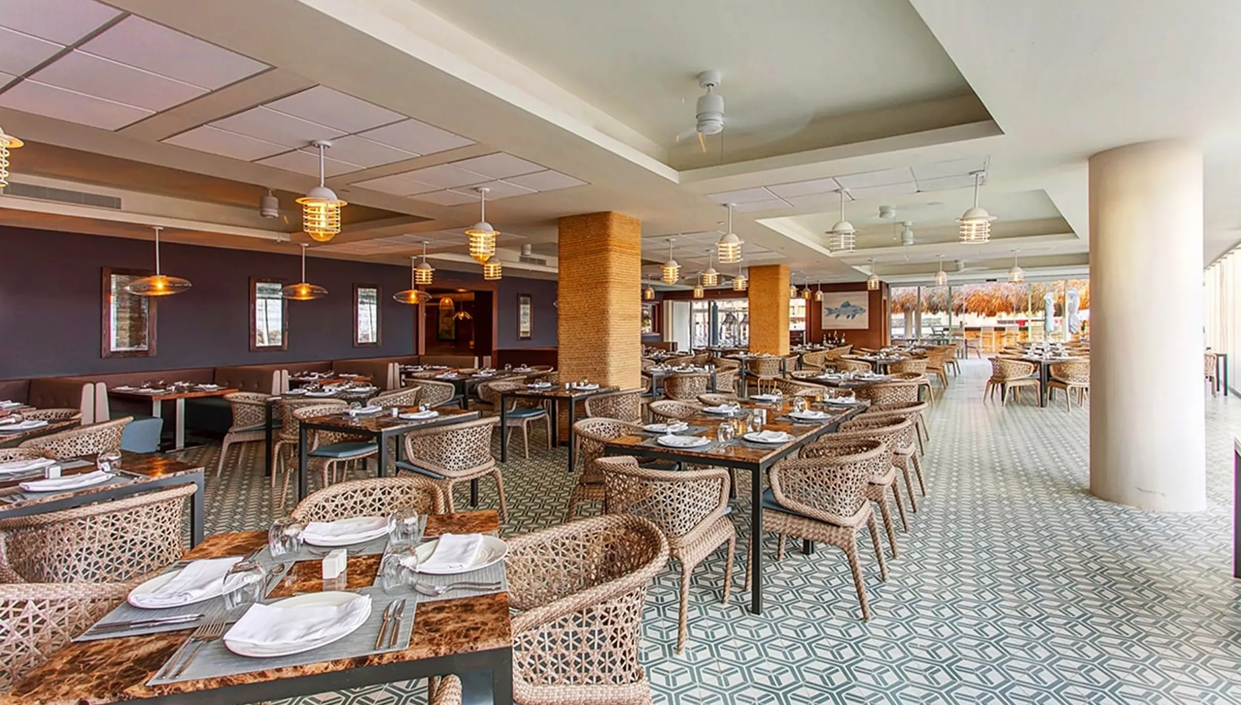 Oceanside restaurant dining area with woven chairs and tiled floors at Royalton Bavaro, Punta Cana