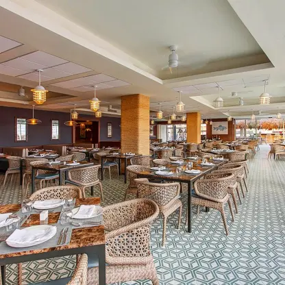 Oceanside restaurant dining area with woven chairs and tiled floors at Royalton Bavaro, Punta Cana