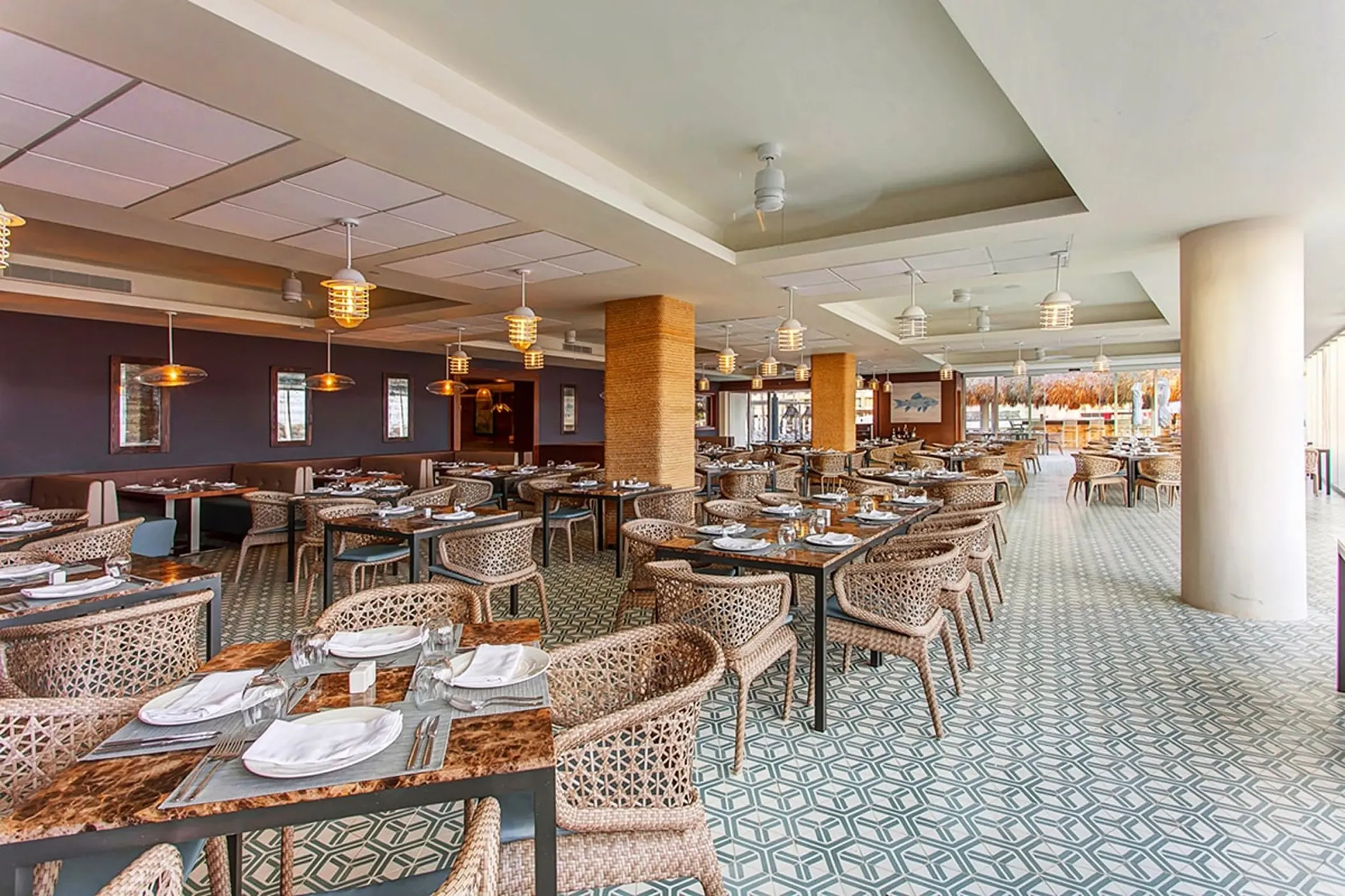 Oceanside restaurant dining area with woven chairs and tiled floors at Royalton Bavaro, Punta Cana