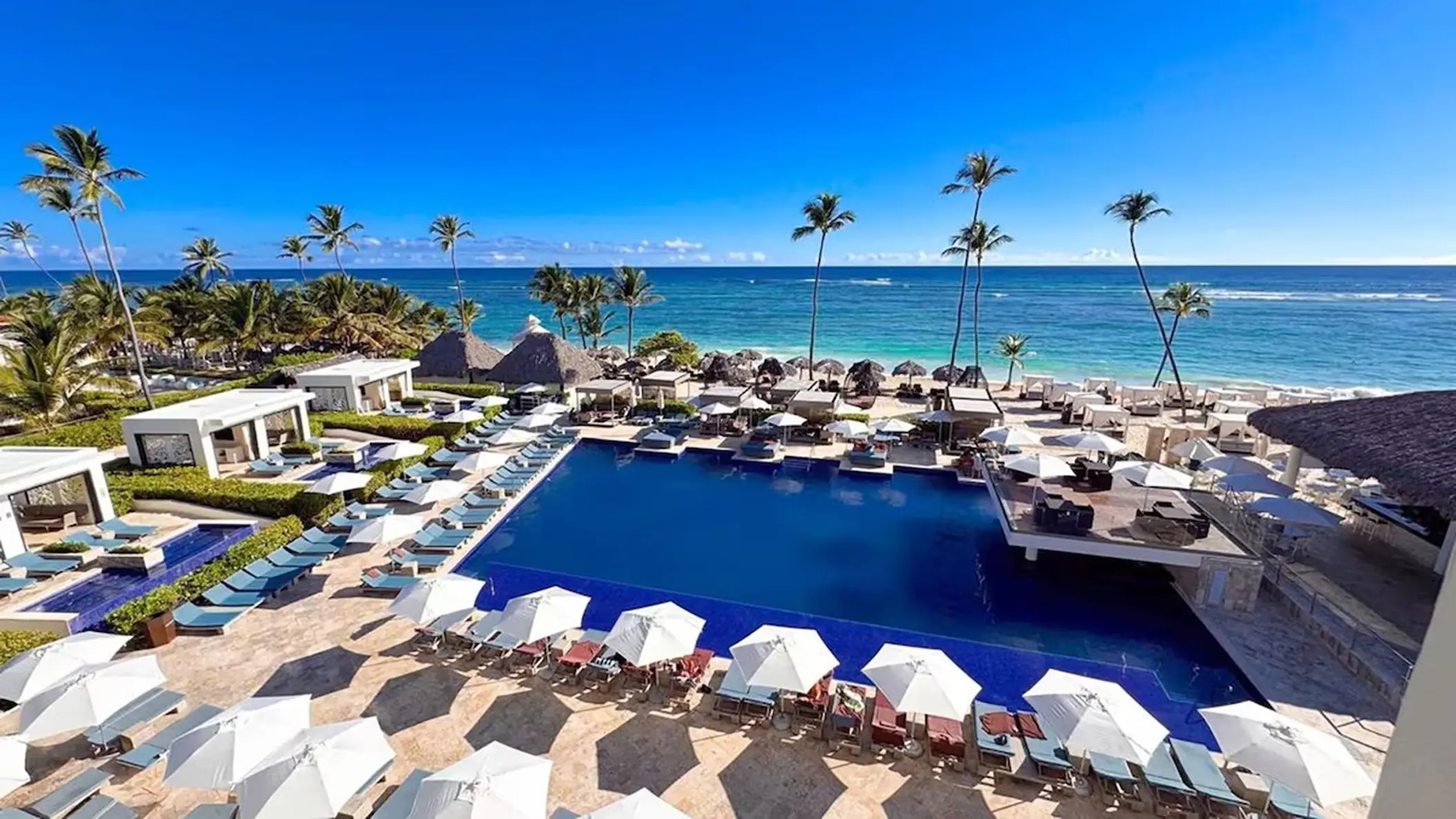 Royalton Bavaro main pool with white umbrellas and palm trees overlooking the ocean, Punta Cana