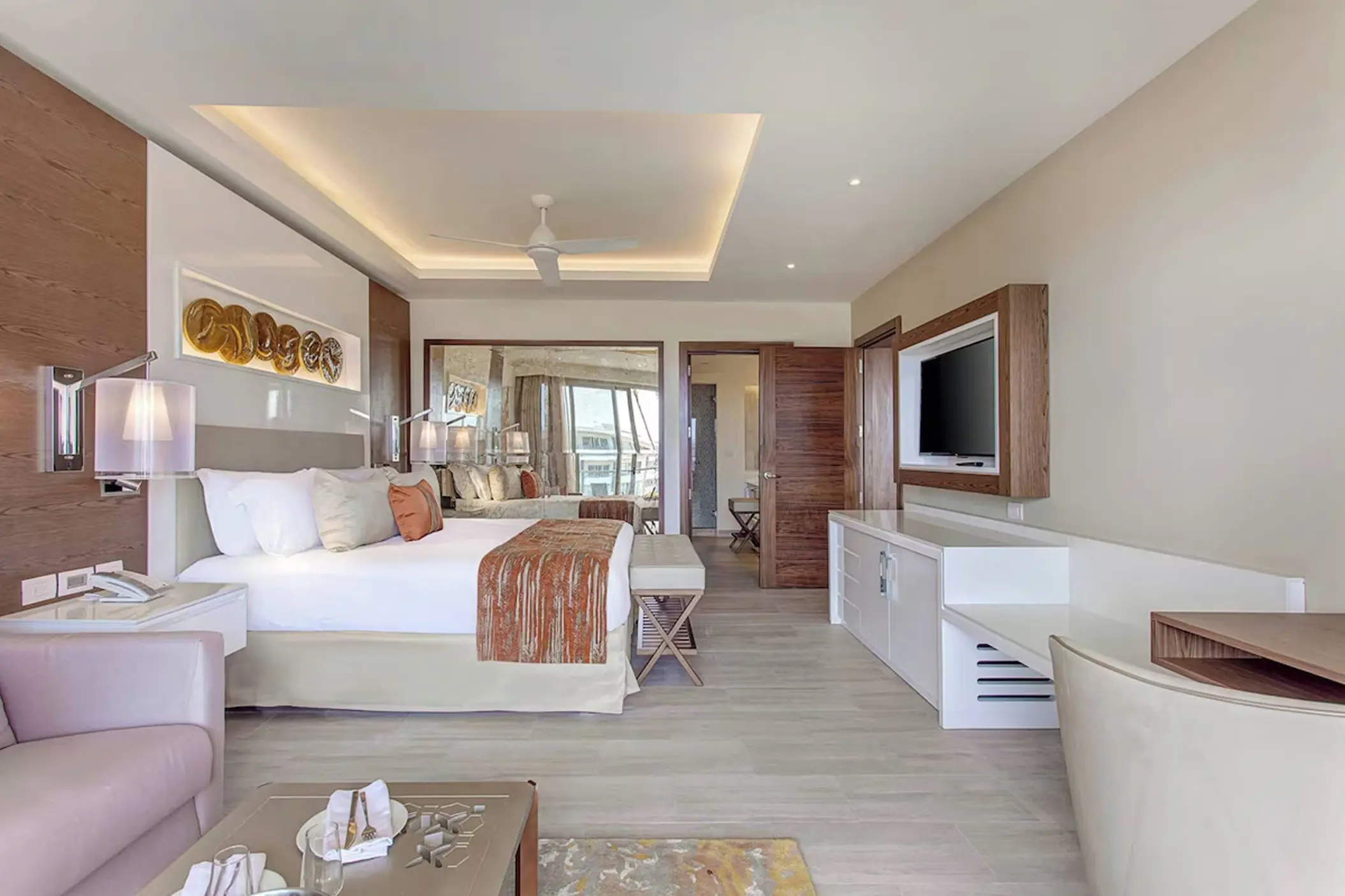 Modern guest room suite with wood accents and a white bed at Royalton Bavaro, Punta Cana