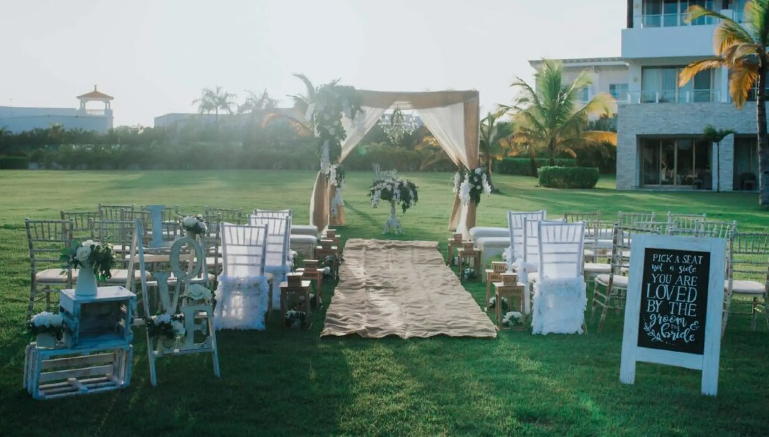 Garden wedding ceremony setup with a draped wooden arch at Royalton CHIC Punta Cana