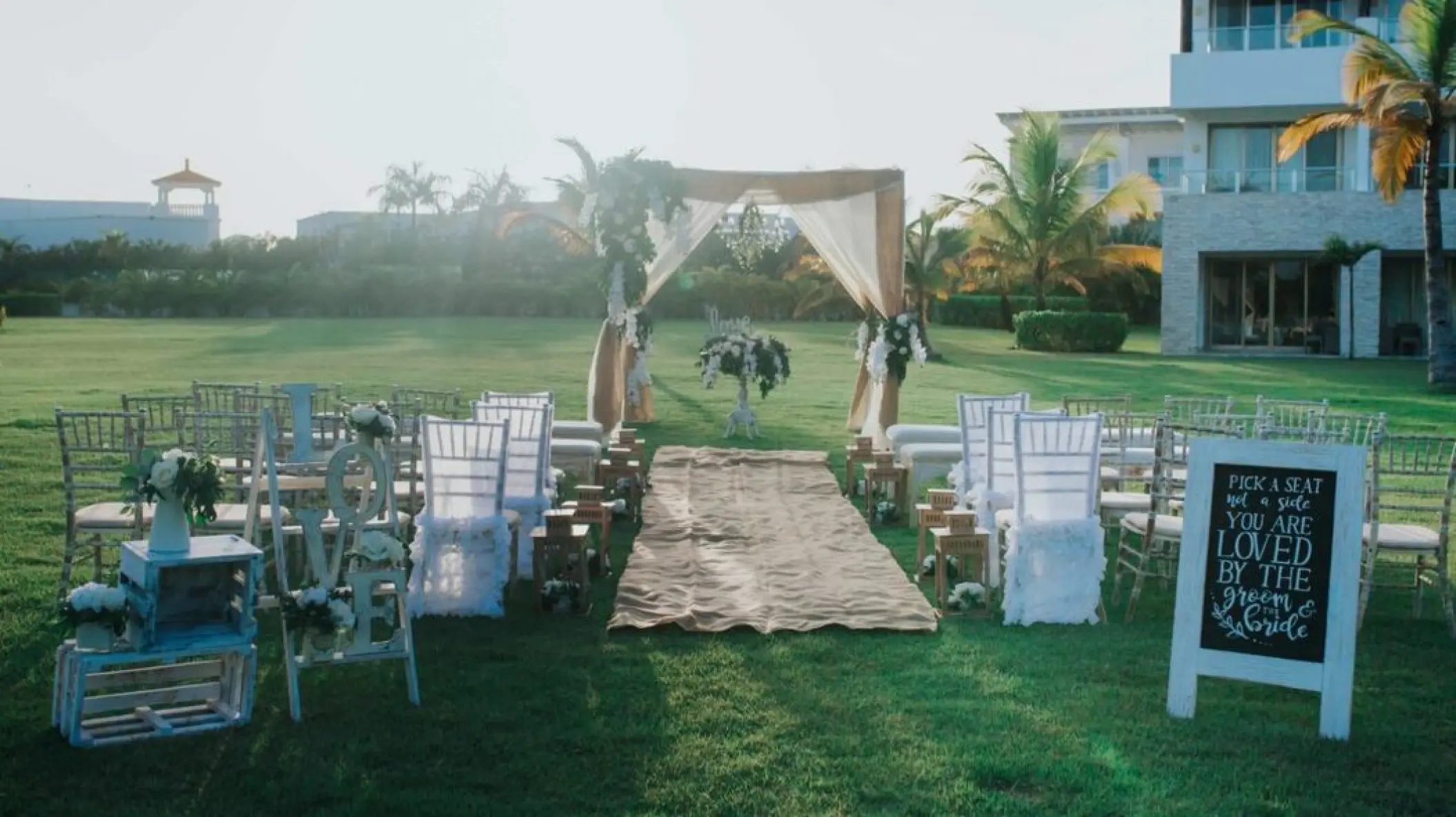 Garden wedding ceremony setup with a draped wooden arch at Royalton CHIC Punta Cana