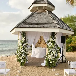 Beachfront wedding ceremony gazebo with white floral pillars at Royalton Grenada, St. George’s
