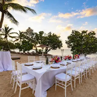 Beach wedding reception setup with long tables and white chairs at Royalton Grenada, St. George’s