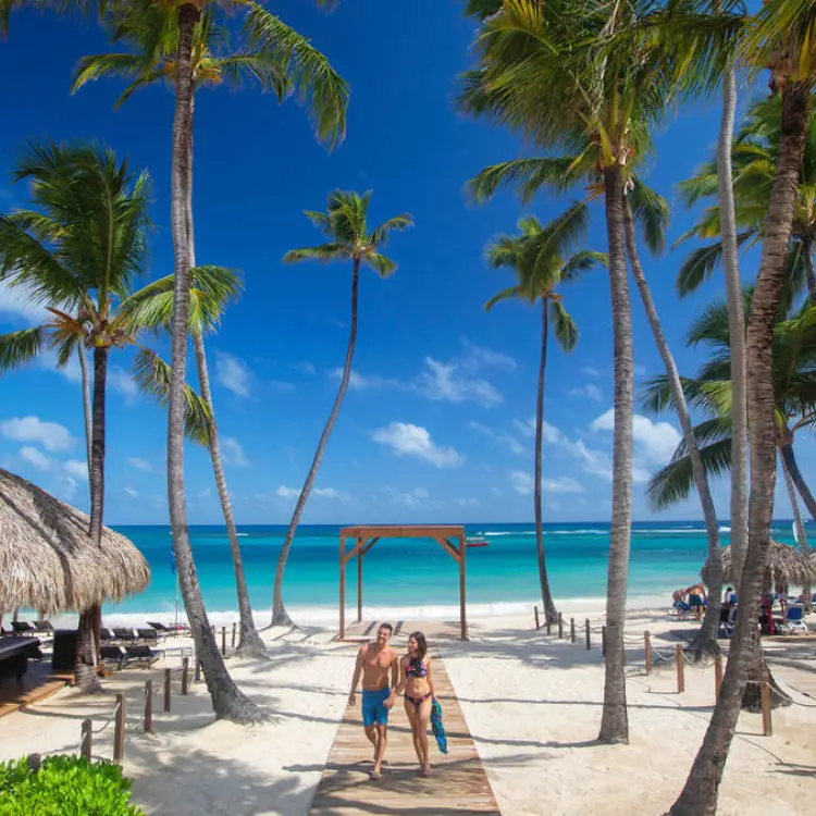 Couple walking on the beach under palm trees at Royalton Punta Cana, Punta Cana