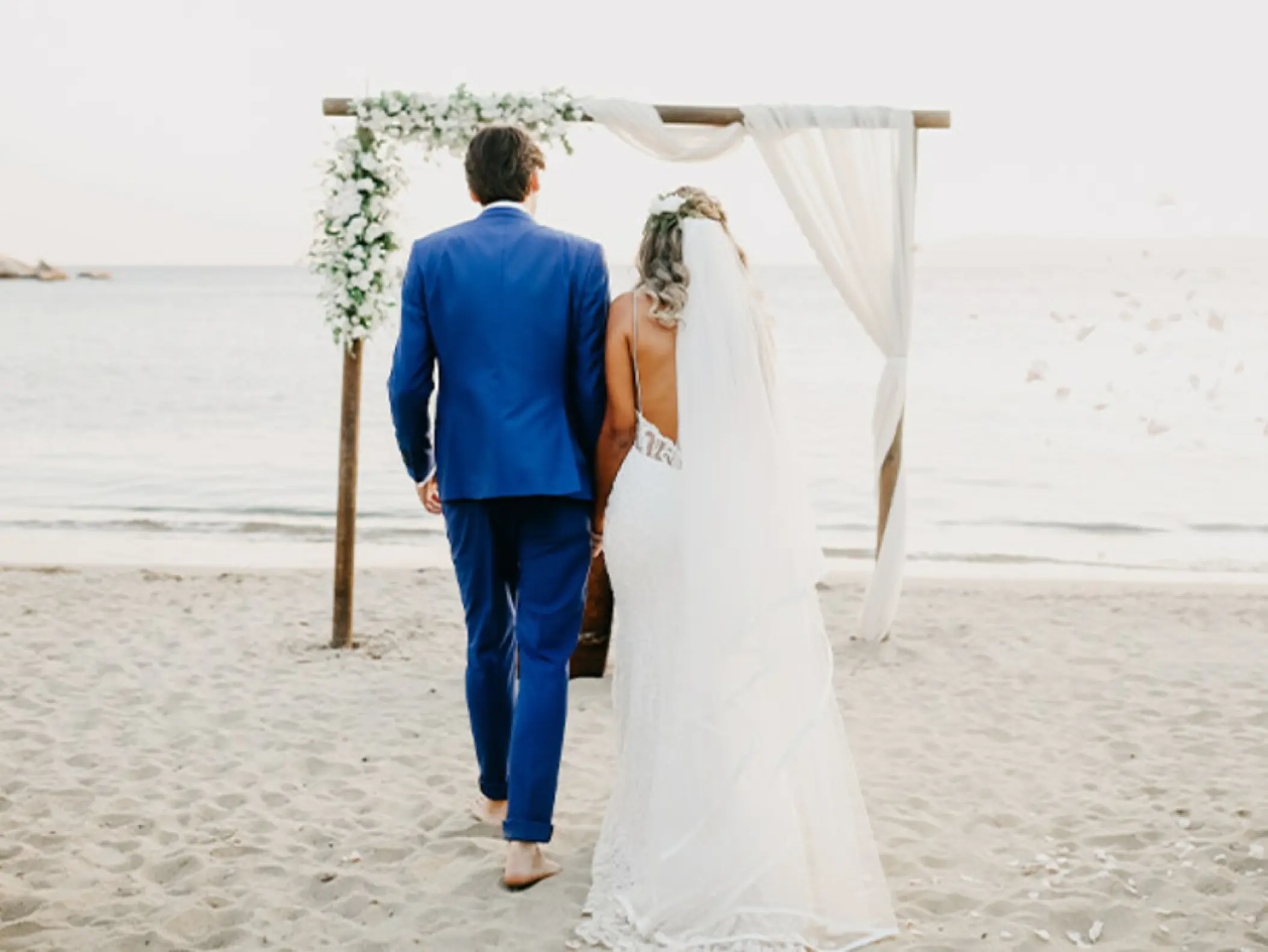 Bride and groom walking toward a beach ceremony arch at Royalton Punta Cana, Punta Cana