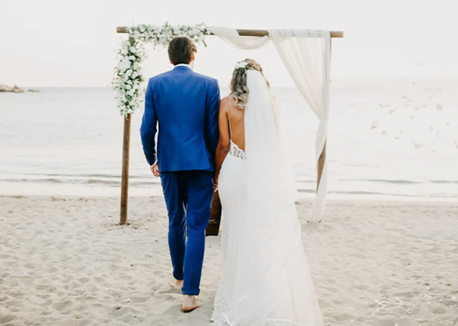 Bride and groom walking toward a beach ceremony arch at Royalton Punta Cana, Punta Cana