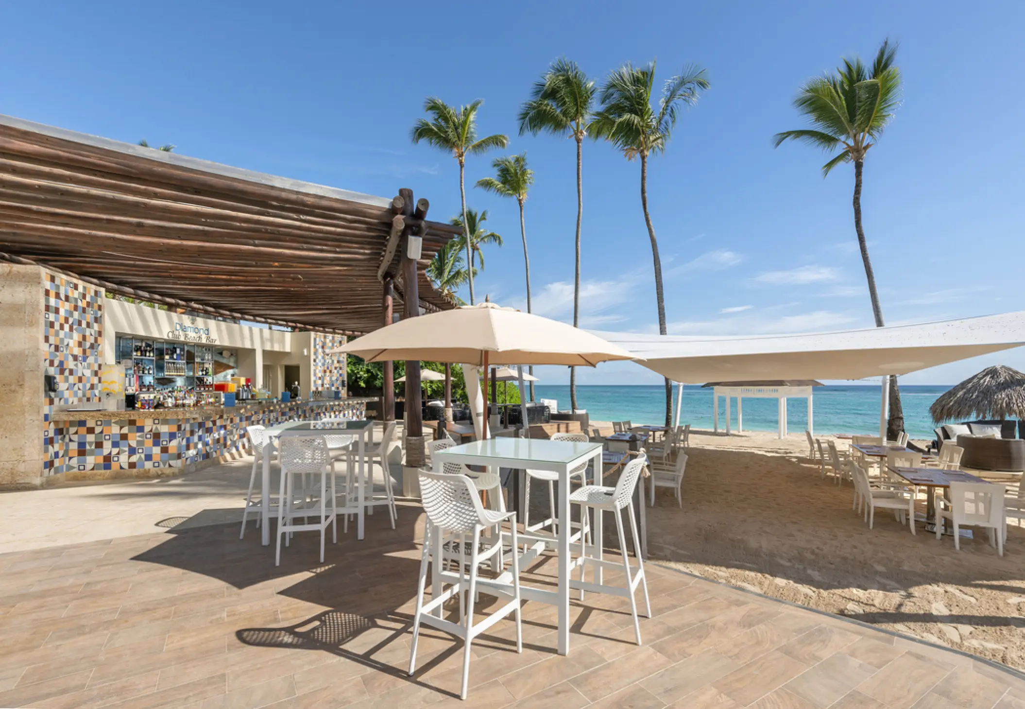 Diamond Club beach bar with white high-top seating and palm trees at Royalton Punta Cana, Punta Cana