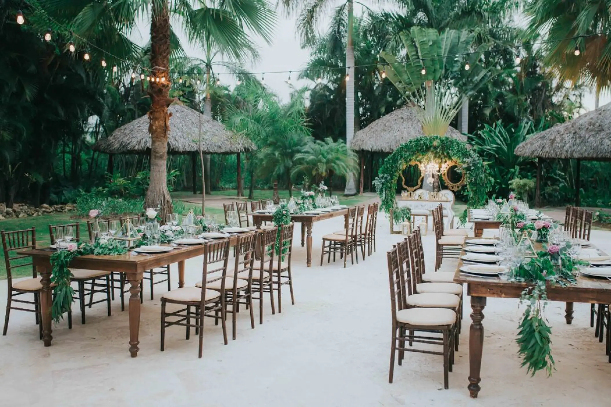 Outdoor garden wedding reception with rustic tables and string lights at Royalton Punta Cana, Punta Cana