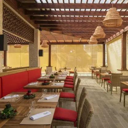 Jade restaurant wedding reception venue with red cushioned seating under a wood pergola at Royalton Punta Cana