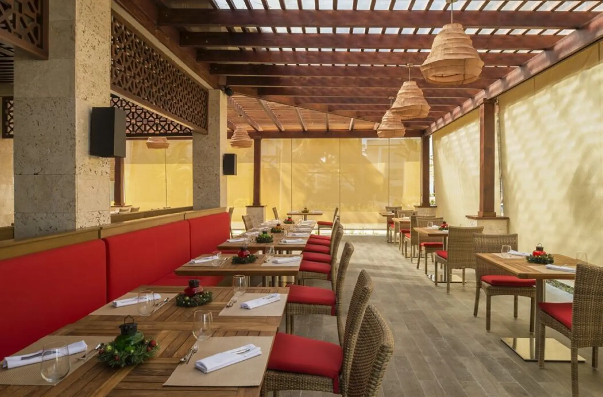 Jade restaurant wedding reception venue with red cushioned seating under a wood pergola at Royalton Punta Cana