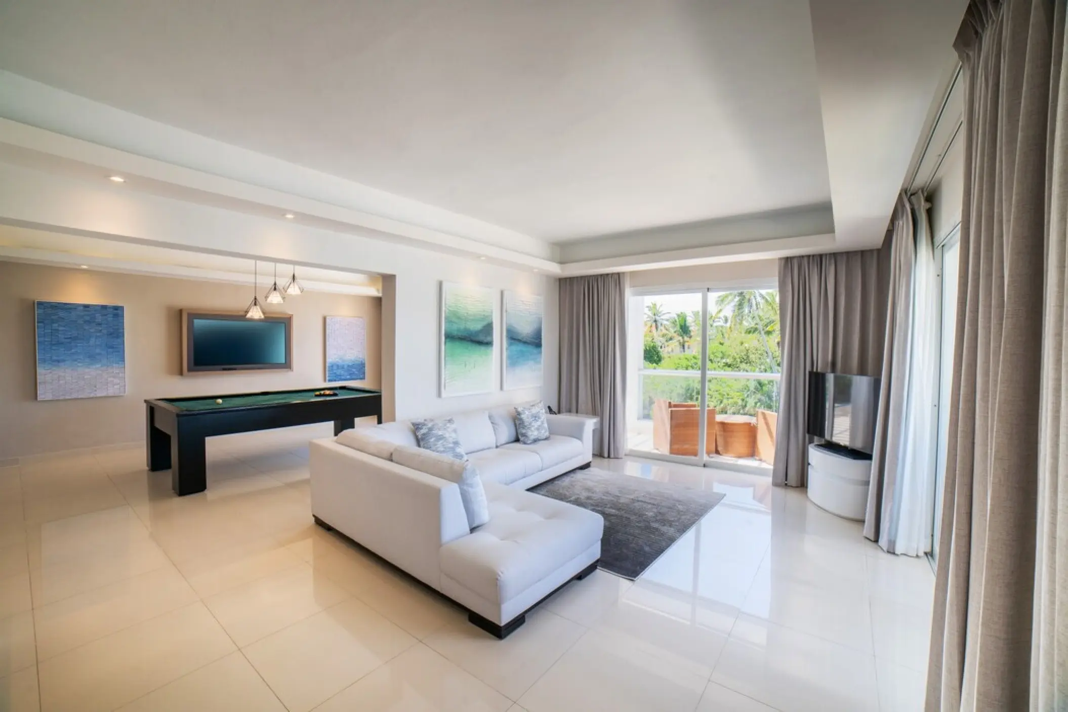 Modern suite living room with white sofa and pool table at Royalton Punta Cana, Punta Cana