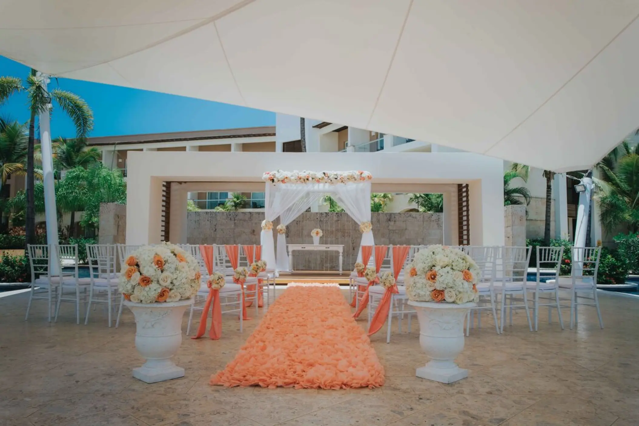 Plaza gazebo wedding ceremony with orange aisle runner and white chairs at Royalton Punta Cana, Punta Cana