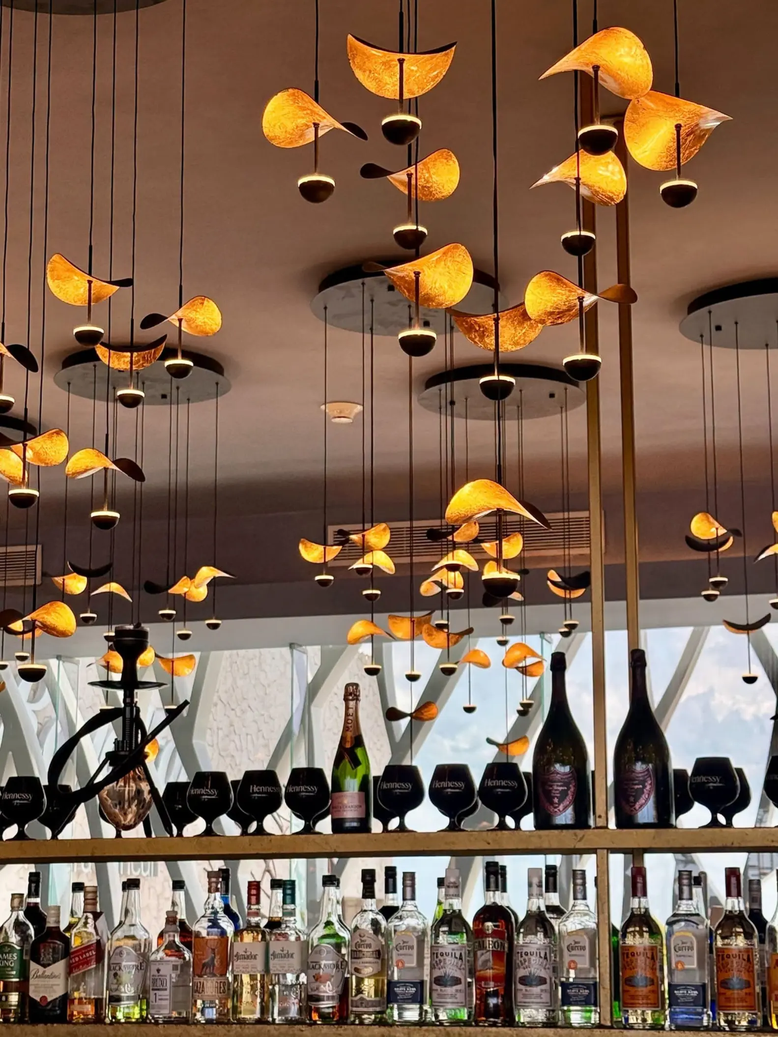 Bar area with hanging orange pendant lights and rows of spirits at Royalton Riviera Cancun, Cancun