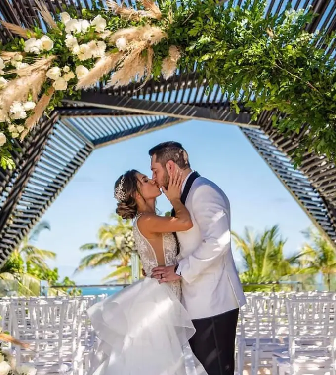 The couple's first kiss under a floral arch at Royalton Riviera Cancun