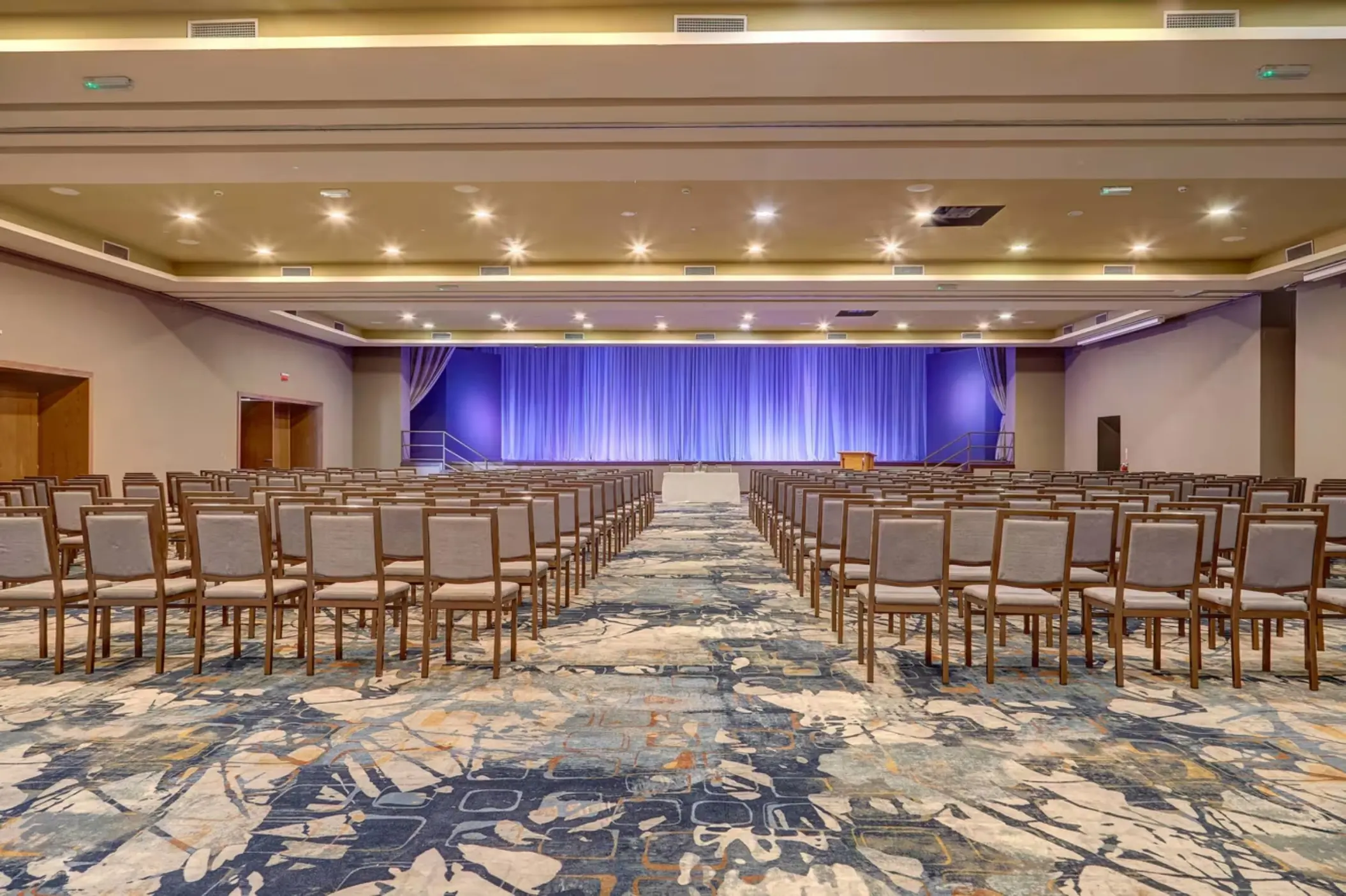 Theater-style conference room setup with rows of chairs and a purple stage at Royalton Saint Lucia, Castries