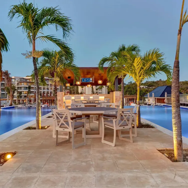 Outdoor seating area and palm trees between swimming pools at Royalton Saint Lucia, Castries