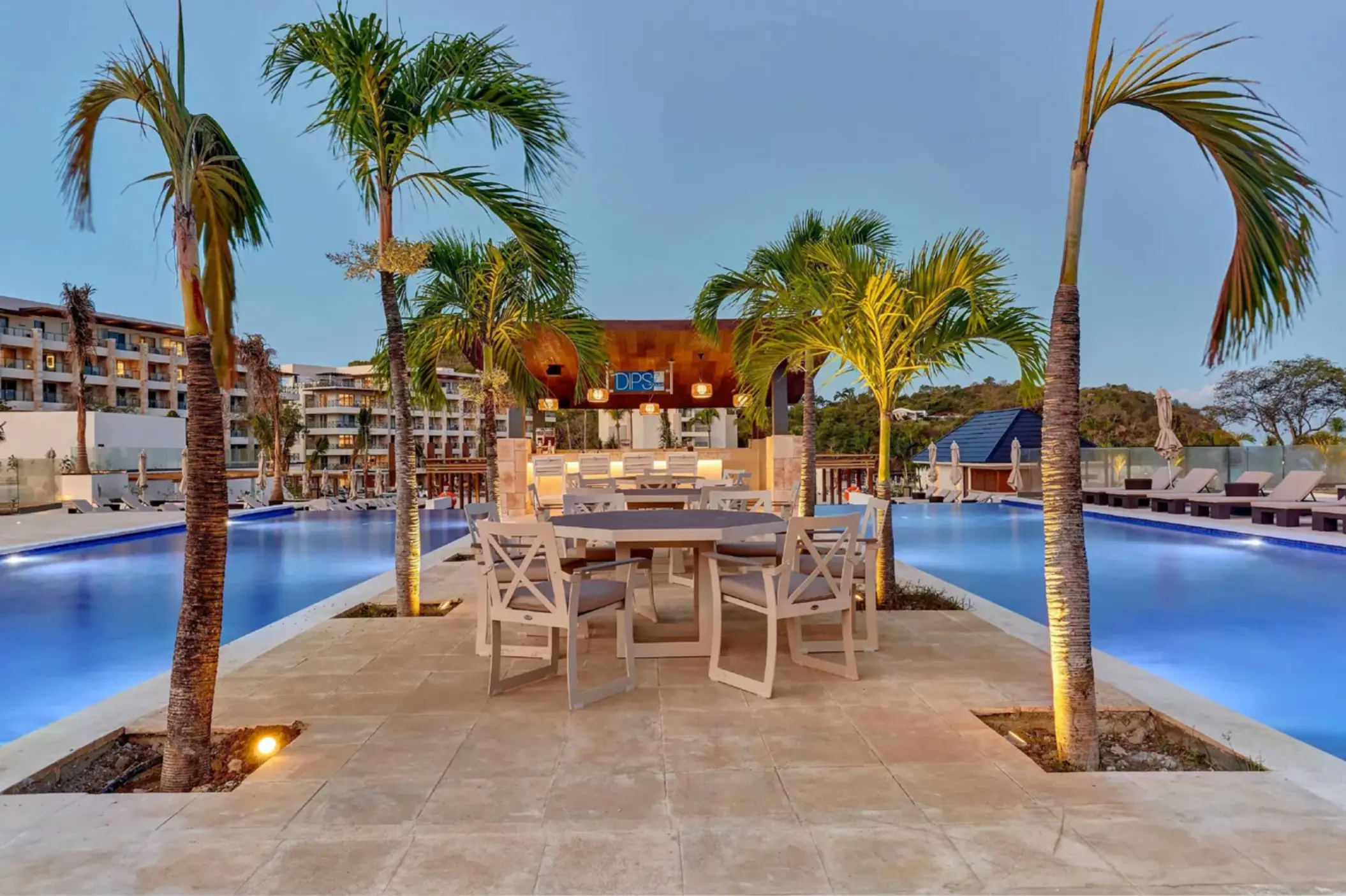 Outdoor seating area and palm trees between swimming pools at Royalton Saint Lucia, Castries