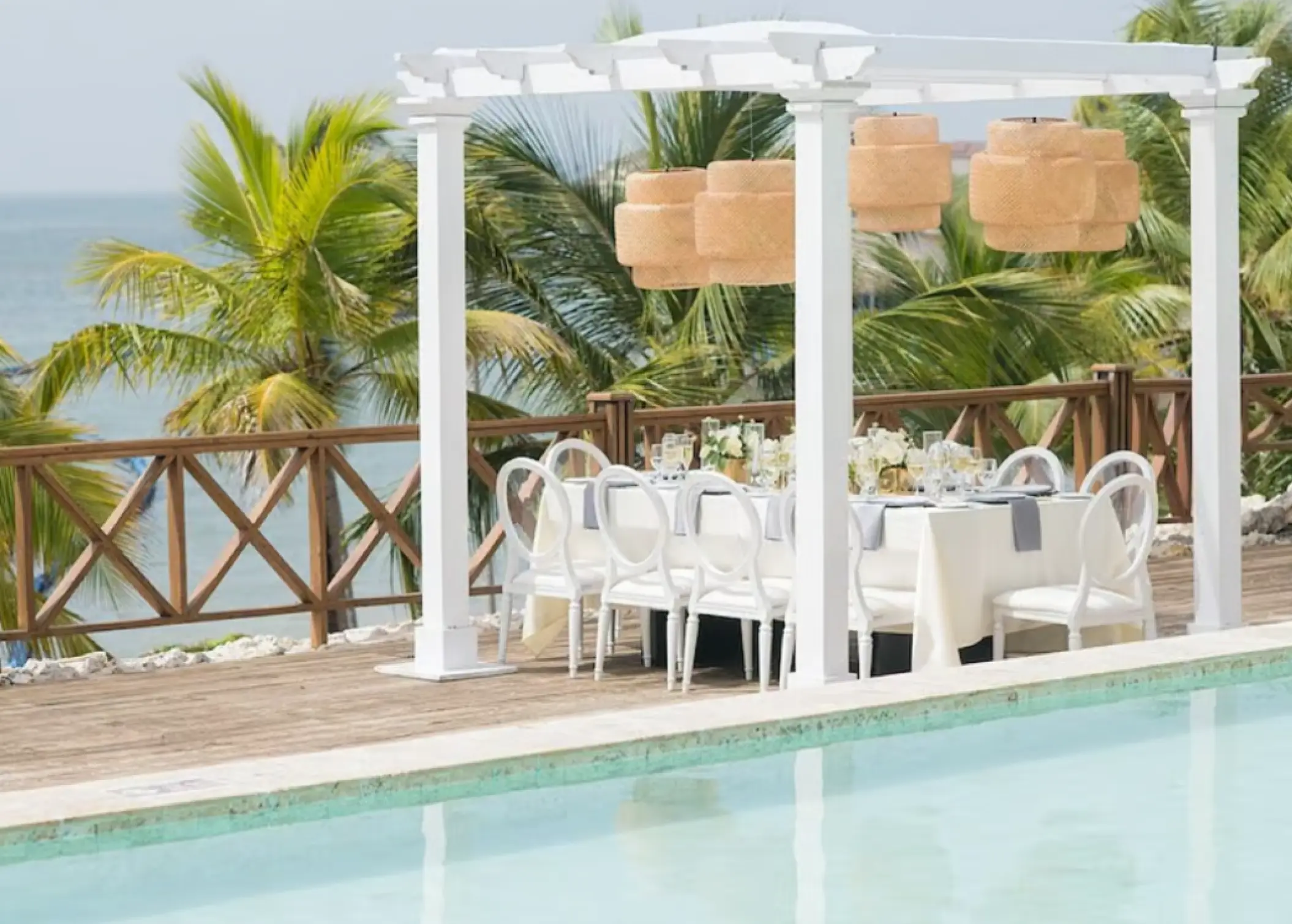 Private wedding reception setup under a white pergola by the pool at Sanctuary Cap Cana, Punta Cana