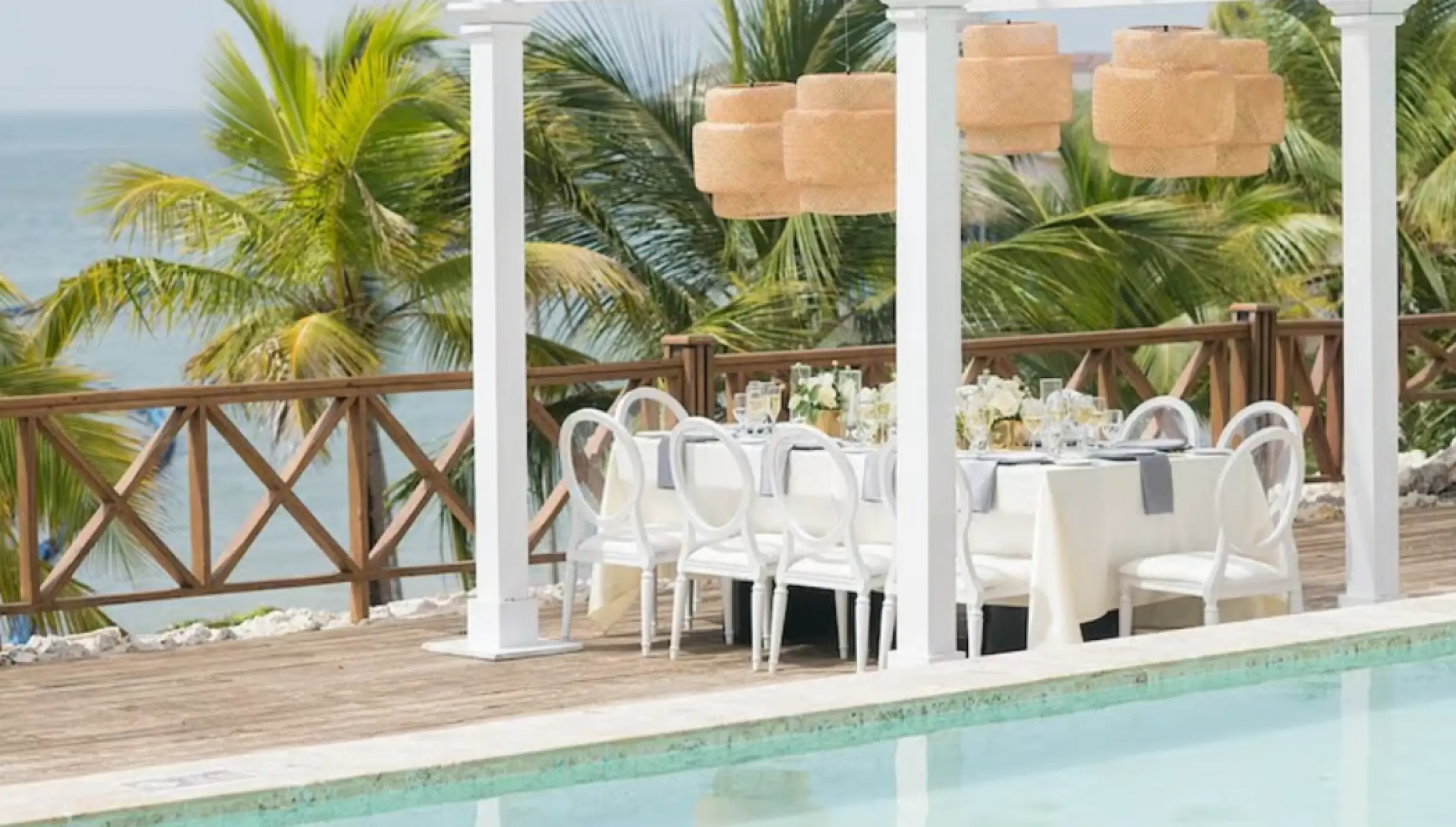 Private wedding reception setup under a white pergola by the pool at Sanctuary Cap Cana, Punta Cana