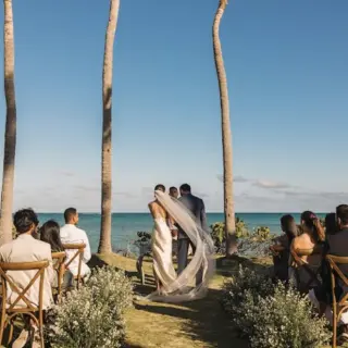 Wedding ceremony at Sanctuary Cap Cana, Punta Cana with ocean views and guests seated under palm trees