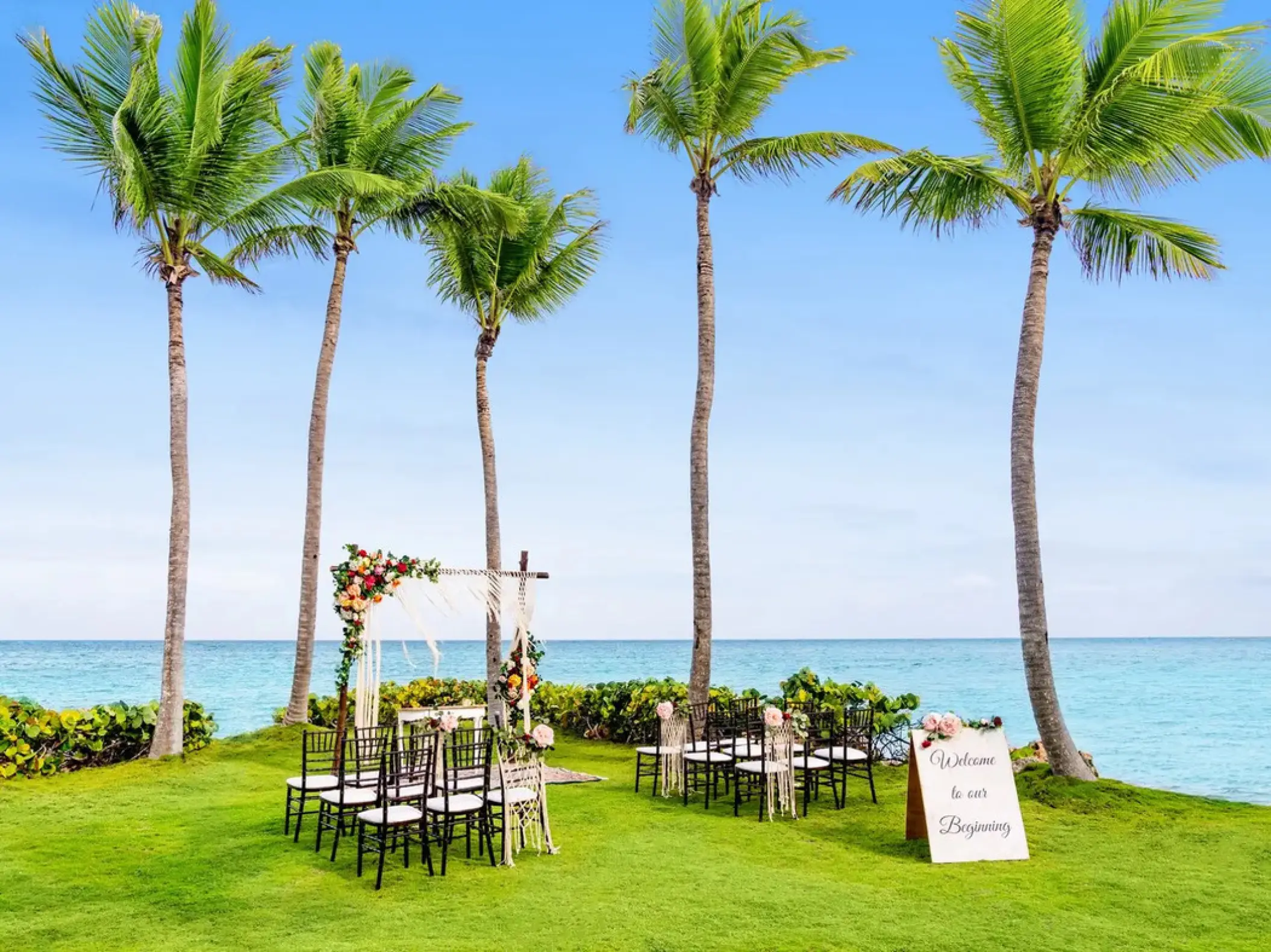 Oceanfront wedding ceremony setup on the lawn with palm trees at Sanctuary Cap Cana, Punta Cana
