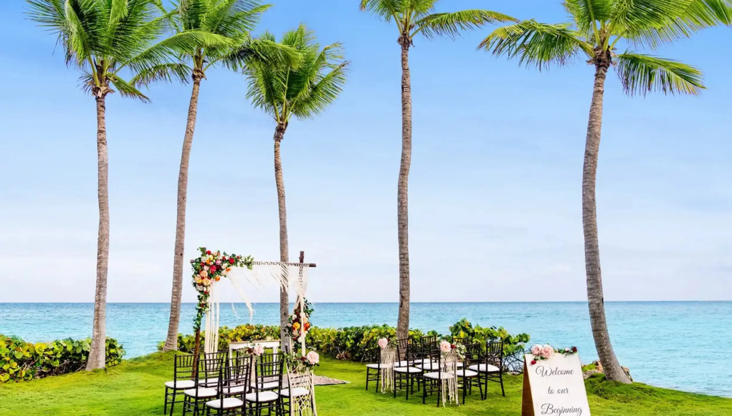 Oceanfront wedding ceremony setup on the lawn with palm trees at Sanctuary Cap Cana, Punta Cana