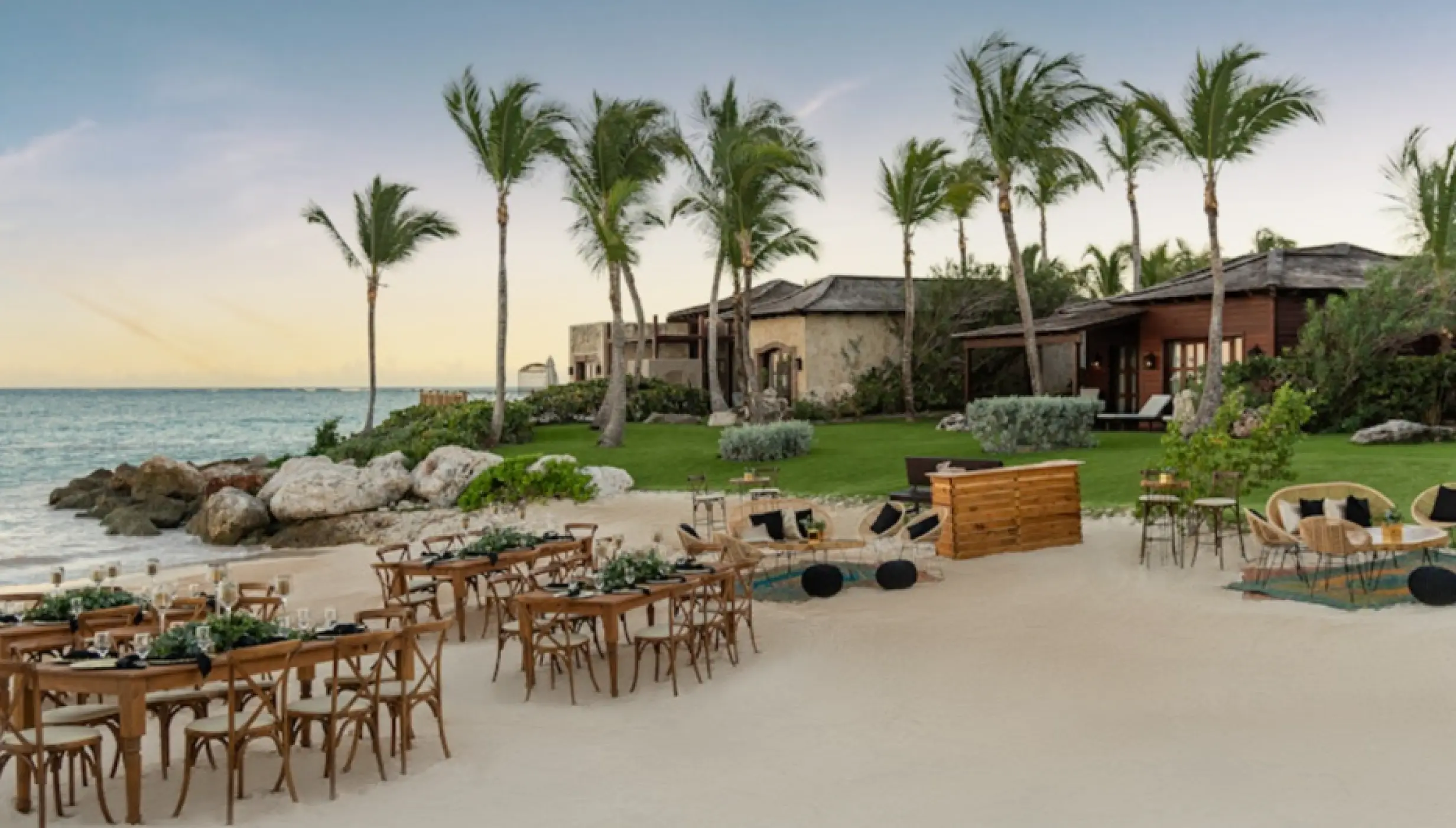 Beachfront wedding reception with wooden tables and palm trees at Sanctuary Cap Cana, Punta Cana