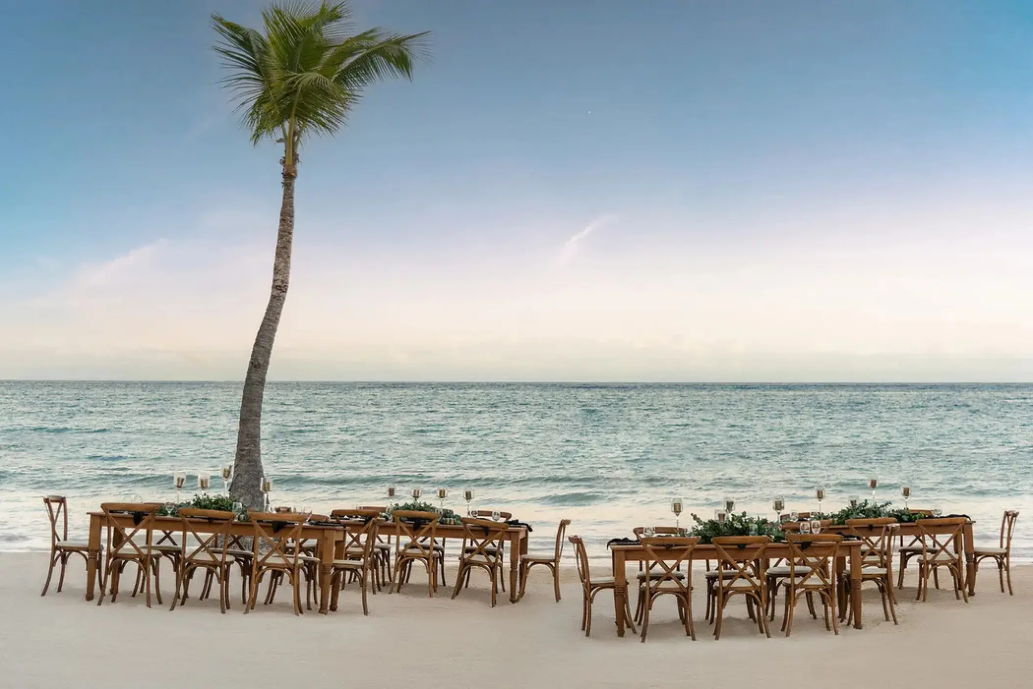 Beachfront wedding reception setup with wooden tables and chairs at Sanctuary Cap Cana, Punta Cana