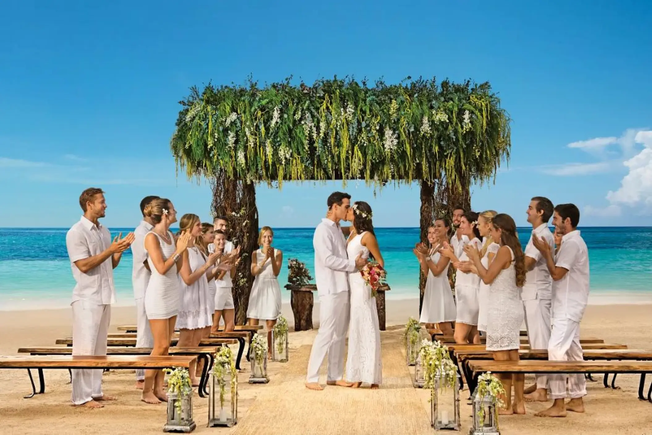 Couple kissing at a beach ceremony with guests at Secrets Akumal, Riviera Maya