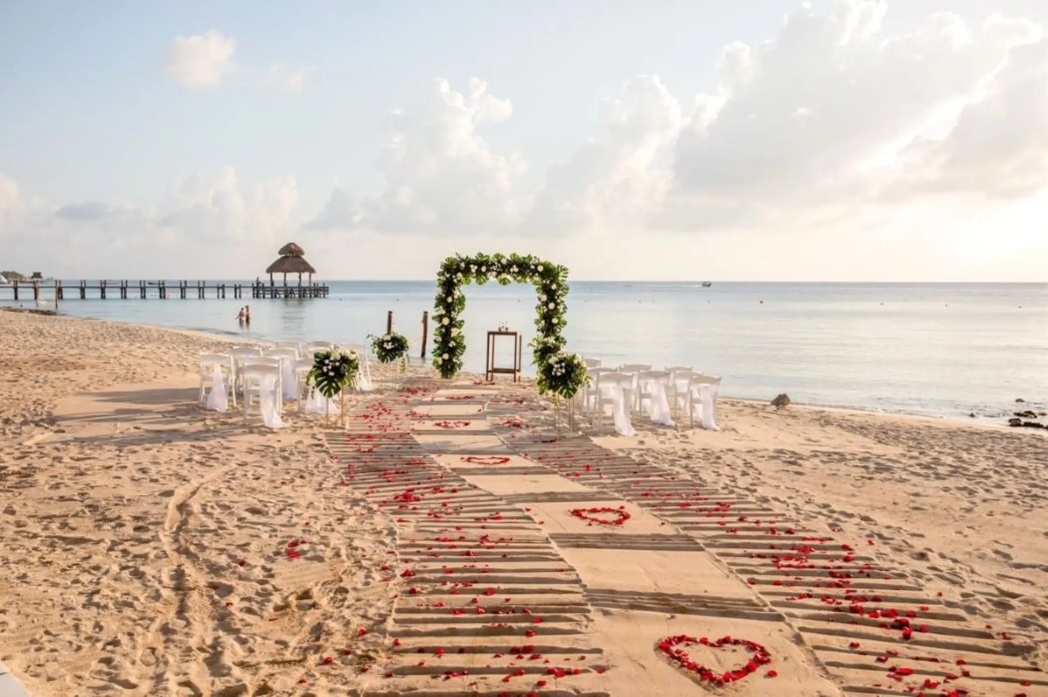 Beachfront wedding ceremony setup with floral arch at Secrets Aura, Cozumel