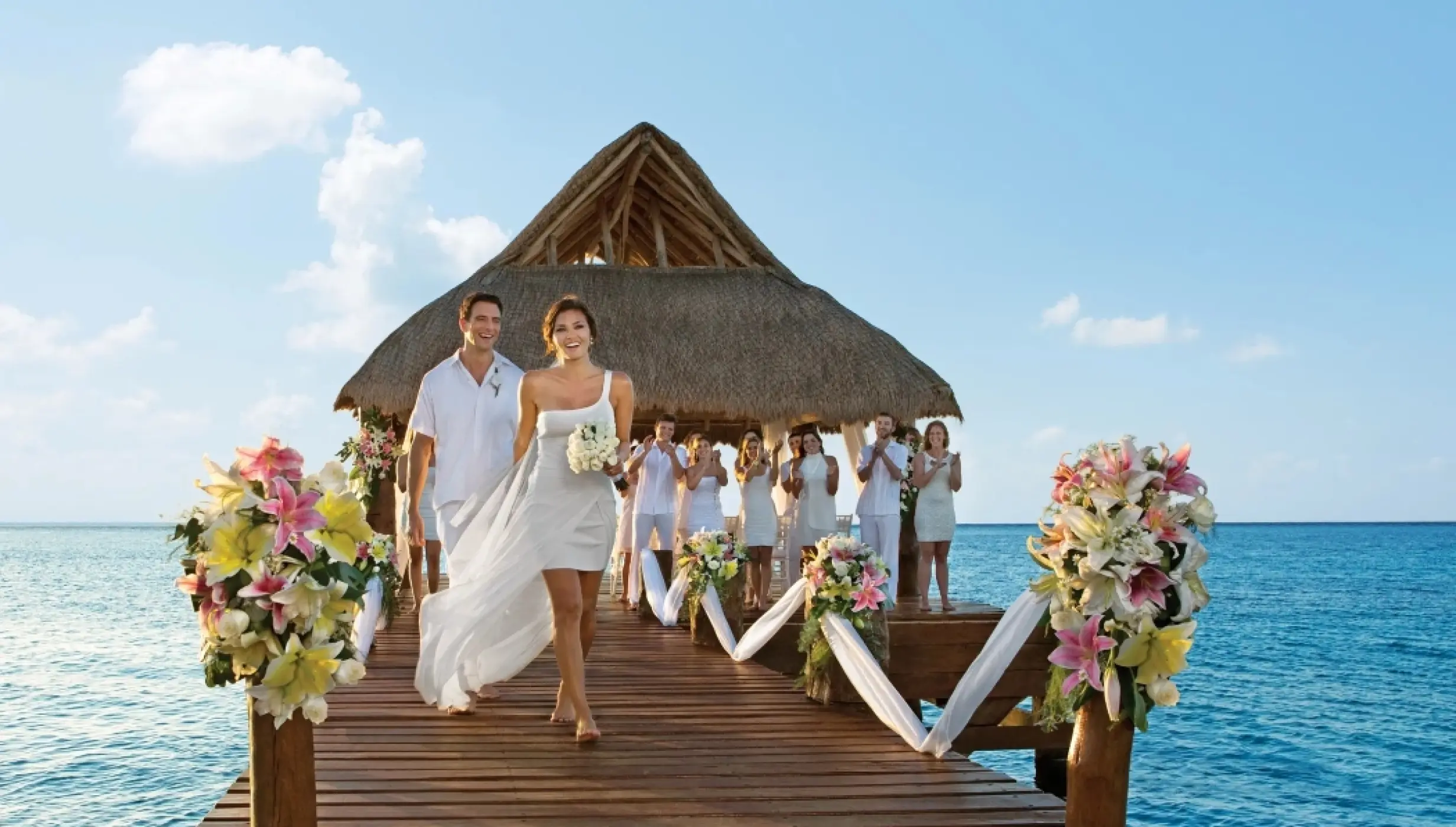 Bride and groom walking down a pier wedding ceremony venue at Secrets Aura Cozumel