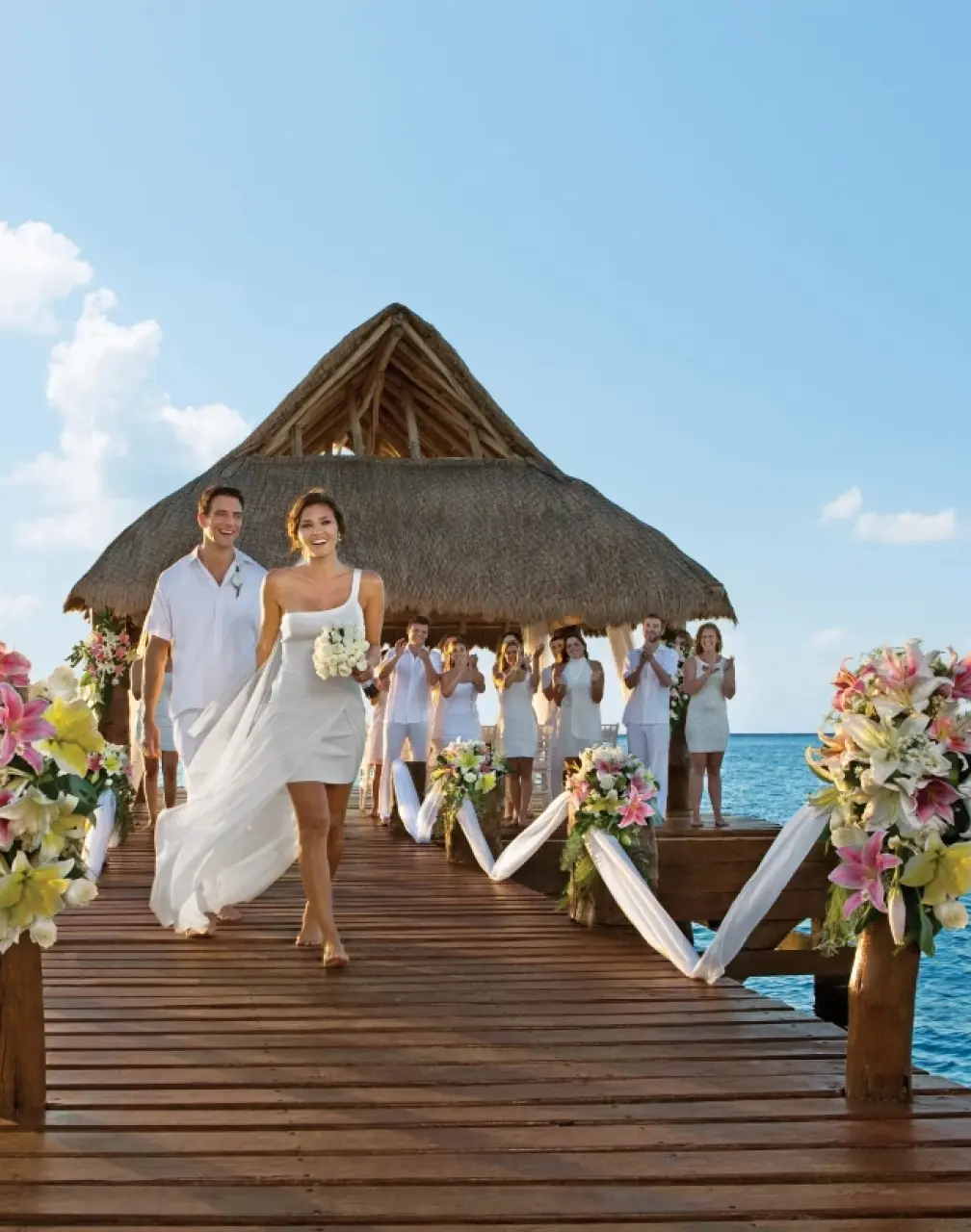 Bride and groom walking down a pier wedding ceremony venue at Secrets Aura Cozumel