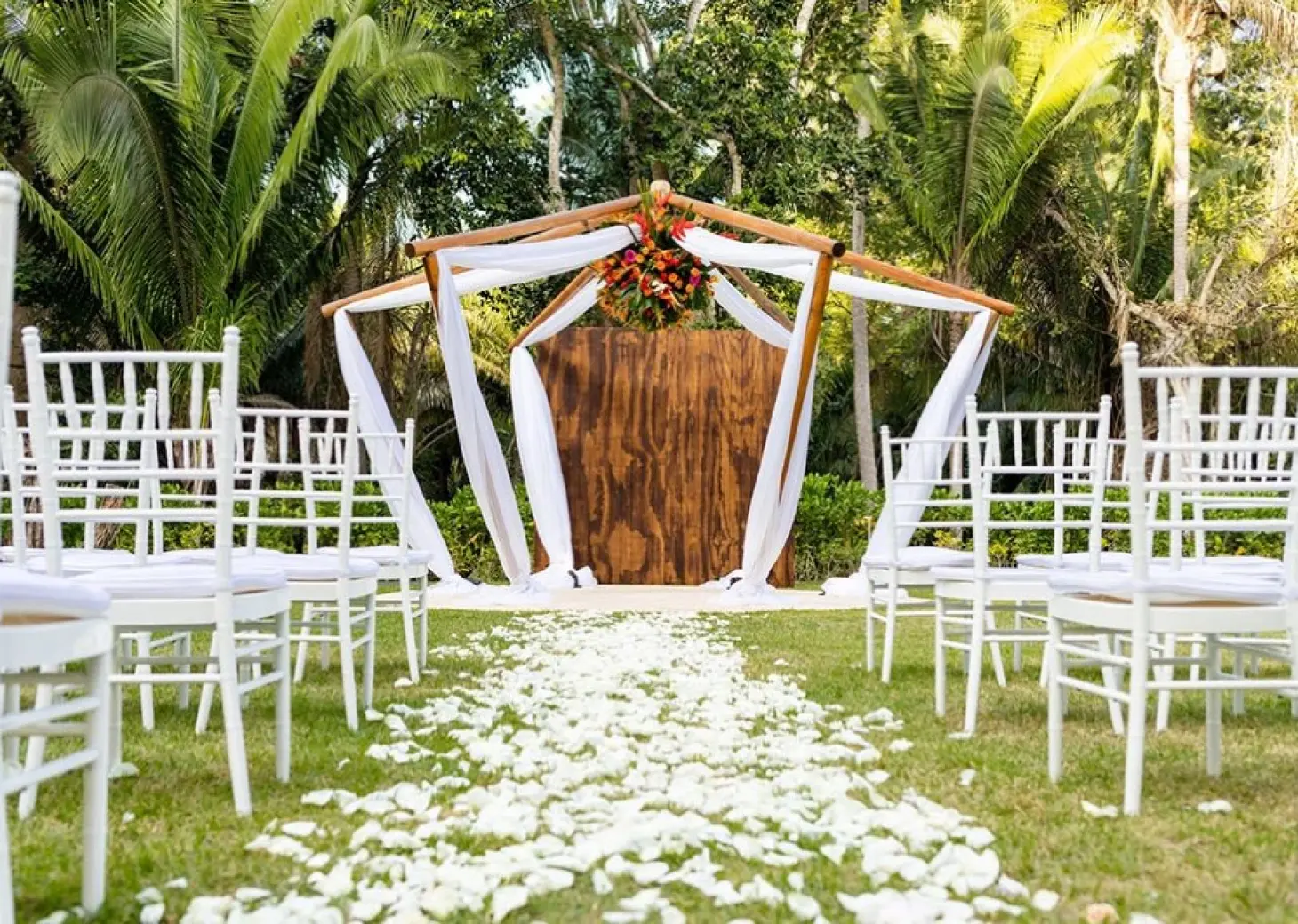 Garden wedding ceremony with white chairs and floral archway at Secrets Bahia Mita, Puerto Vallarta