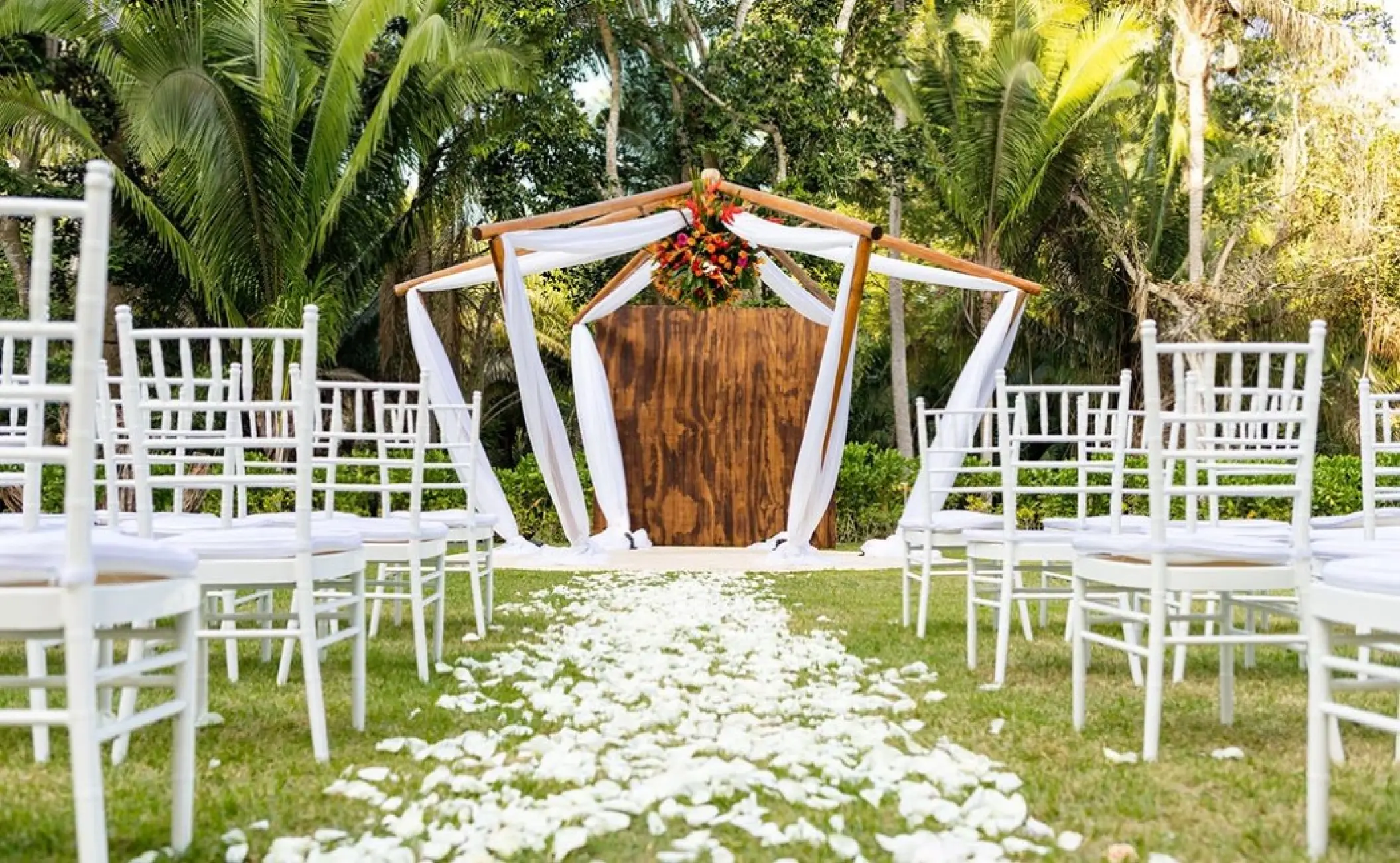 Garden wedding ceremony with white chairs and floral archway at Secrets Bahia Mita, Puerto Vallarta