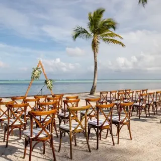 Beachfront wedding ceremony with wooden cross-back chairs at Secrets Cap Cana, Punta Cana