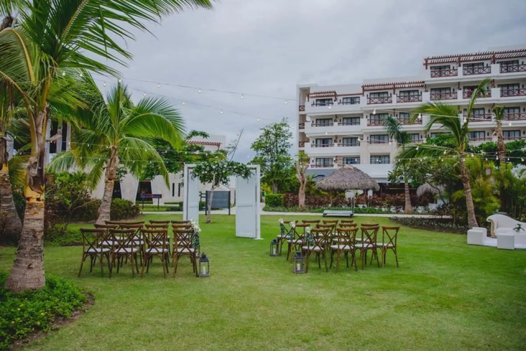 Garden wedding ceremony setup with white doors and wooden chairs at Secrets Cap Cana, Punta Cana