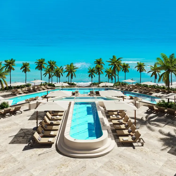 Secrets Mirabel pool deck with lounge chairs and palm trees by the ocean, Cancun